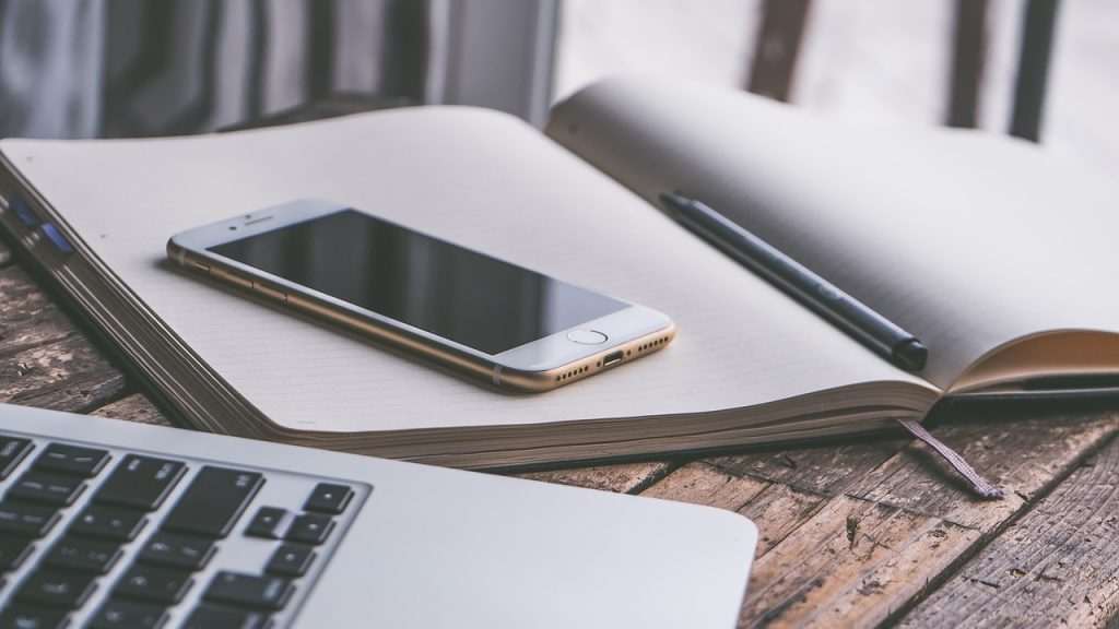 Ordenador portátil y teléfono móvil sobre una mesa, representando la gestión de la presencia digital y el SEO local de un negocio en la era de la IA.